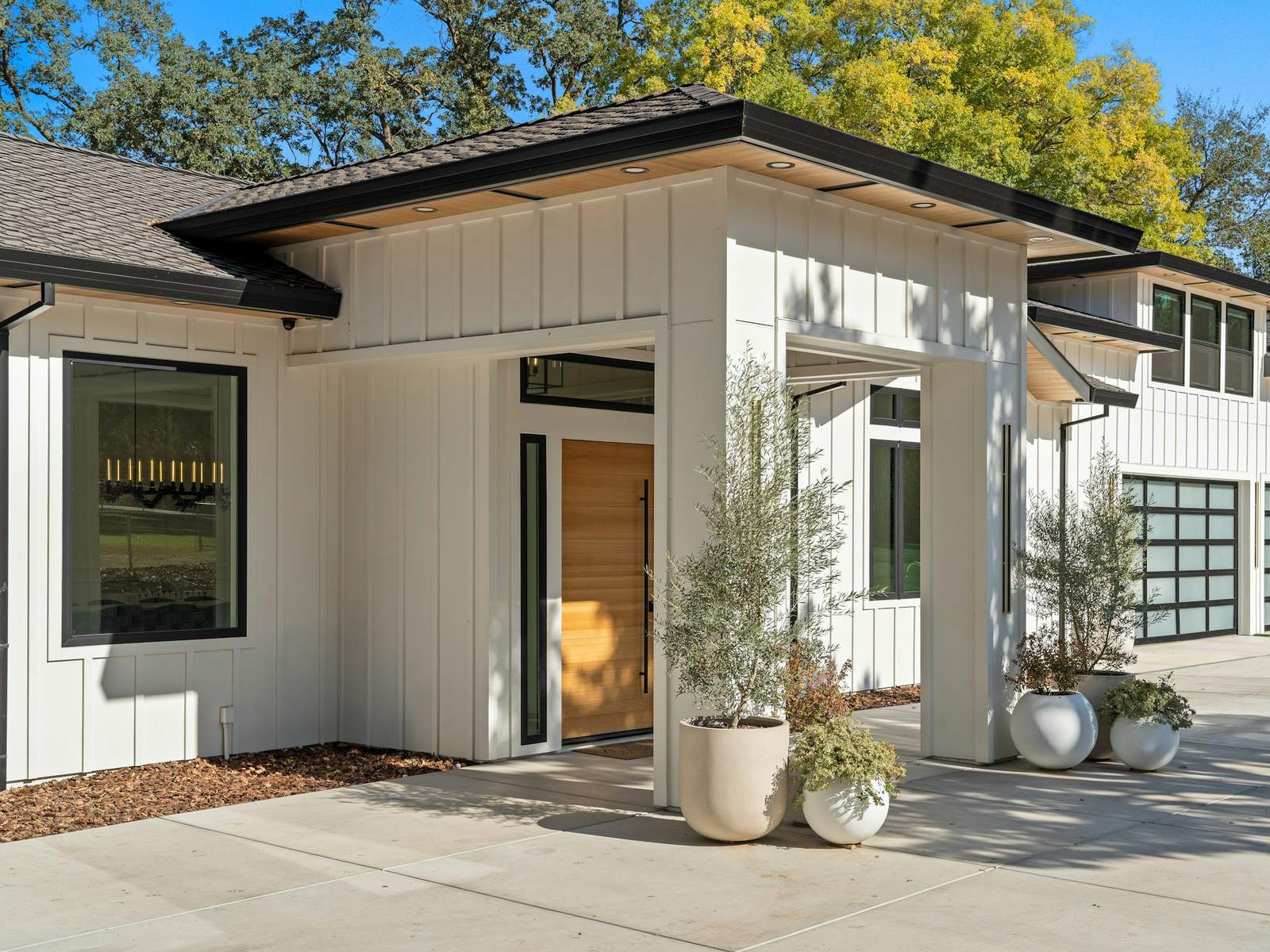 White board-and-batten entry with black trim and a cedar door, illustrative stock photo
