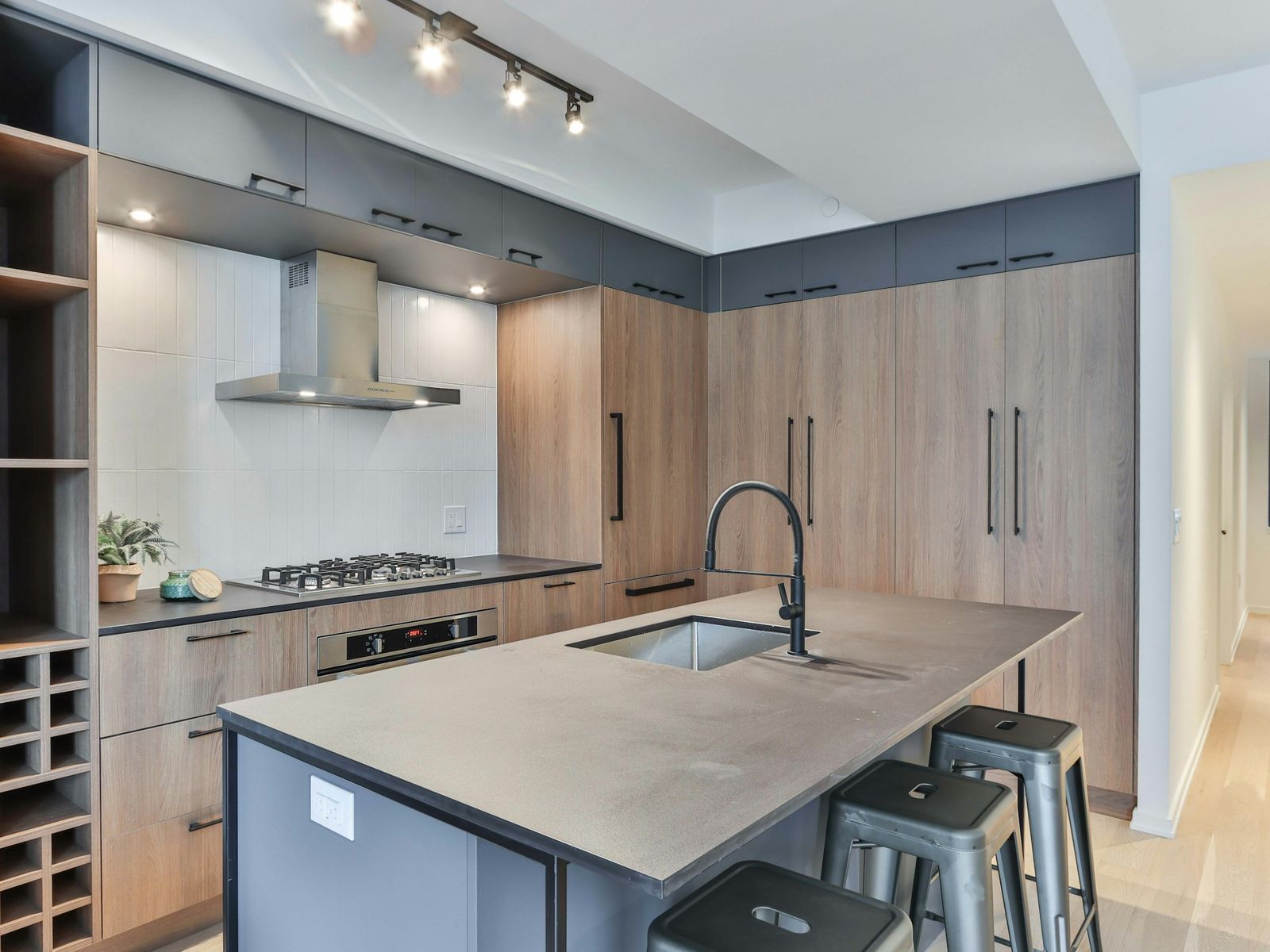 Oak-tone cabinets to the ceiling with matte black pulls and a concrete-look island, illustrative stock photo
