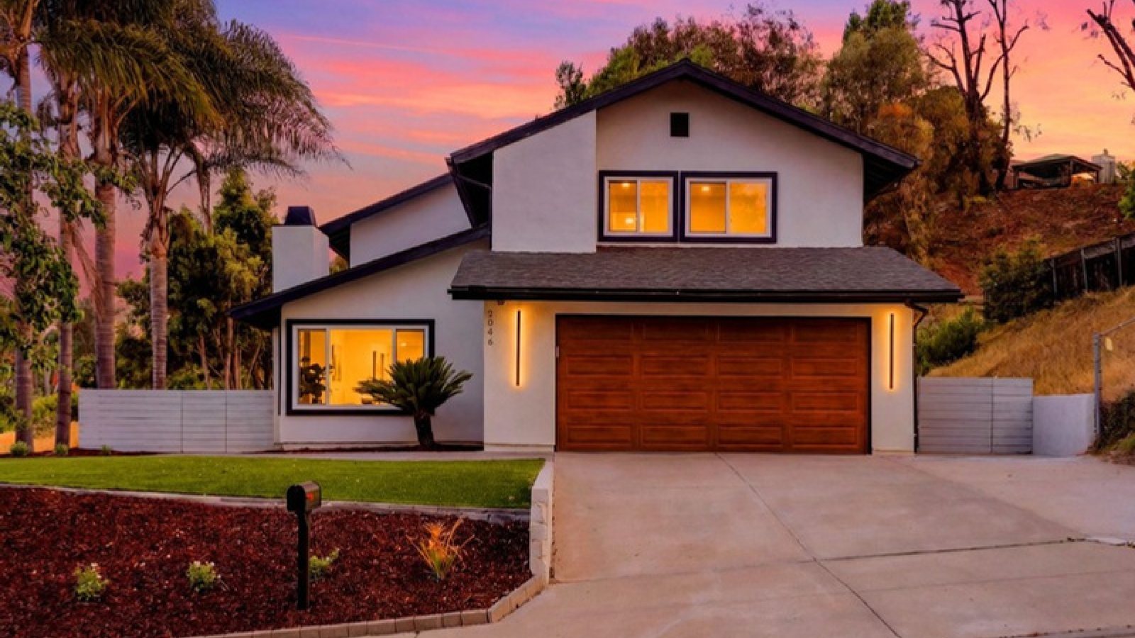 A two-storey home exterior at dusk, with an attached two-car garage